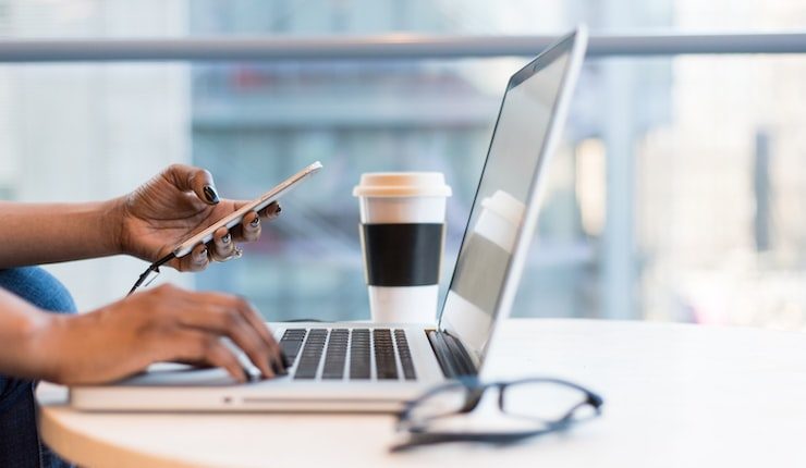 person using smartphone and MacBook