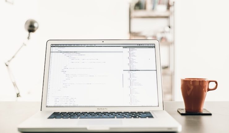 MacBOok Pro beside brown mug