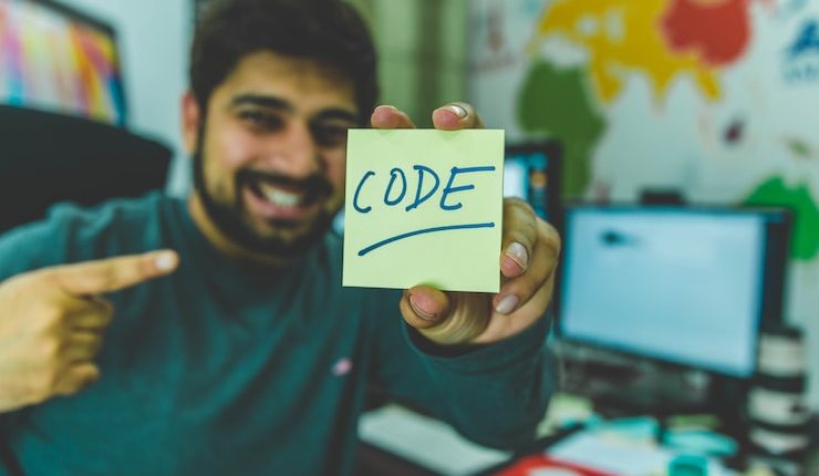 smiling man showing sticky note with code illustration